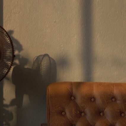 Ventilador de pedestal al lado de un sofá de piel marrón