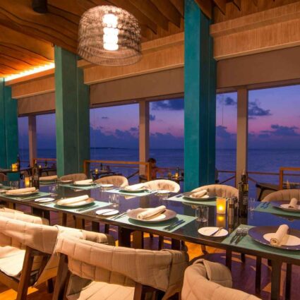 Imagen del interior de un restaurante con las luces encendidas y vistas al mar