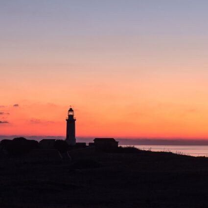 Imagen de un faro en la costa al atardecer.